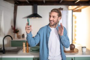 smiling man recording a video message at home 2021 09 04 06 52 29 utc scaled 1